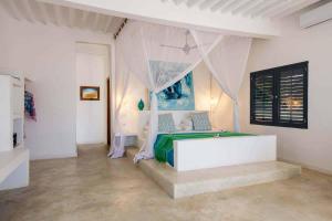 Upendo Beach Boutique Hotel Zanzibar في ميتشامفي: غرفة نوم بسرير مع مظلة