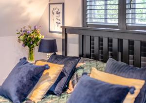 a bedroom with a bed with blue pillows and a vase of flowers at Autumn Barn Annexe in Smarden