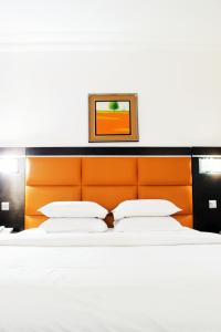 1 dormitorio con 1 cama grande y cabecero naranja en Cata Apartment Hotel And Spa, en Ikeja