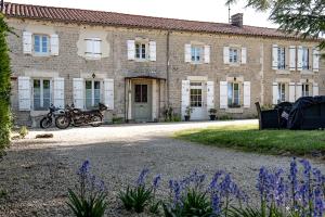 a large brick building with motorcycles parked in front of it at ESCALE AU CLOS SAINT MARTIN DE JUILLERS Gîtes et Chambres d'hôtes in Saint-Martin-de-Juillers