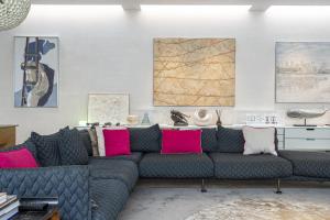 ein Wohnzimmer mit einem grauen Sofa und rosa Kissen in der Unterkunft JOIVY Architectural gem with pool and terrace in West London in London