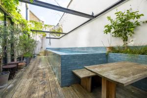 eine Bar im Freien mit einem Holztisch und Bänken in der Unterkunft JOIVY Architectural gem with pool and terrace in West London in London