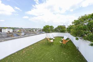 2 Stühle auf einem Balkon mit grünem Gras in der Unterkunft JOIVY Architectural gem with pool and terrace in West London in London