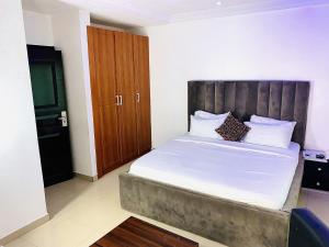 Schlafzimmer mit einem großen Bett mit einem Kopfteil aus Holz in der Unterkunft Vintage Classic Lodge in Lagos