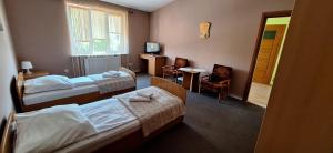 a hotel room with two beds and a table and chairs at Hotel Grodzki in Sandomierz