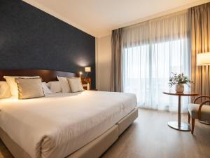 a bedroom with a large bed and a large window at Hotel Spa Galatea in Portonovo