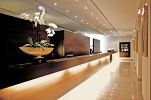 eine Lobby mit einer langen Theke mit einer Blumenvase darauf in der Unterkunft Metropolitan Hotel by Flemings in Frankfurt am Main