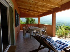 een terras met een tafel en stoelen op een balkon bij Promesse de vacances réussies in Calcatoggio