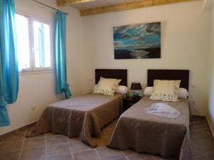 twee bedden in een kamer met blauwe gordijnen bij Promesse de vacances réussies in Calcatoggio