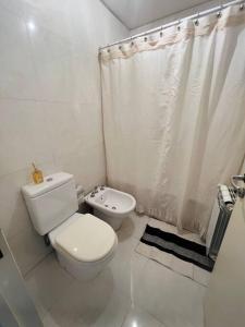 a white bathroom with a toilet and a shower curtain at Depto. a estrenar en Mendoza. in Las Heras