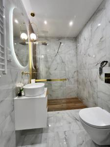 Baño blanco con lavabo y aseo en Apartament Klonova Park 51 en Olecko