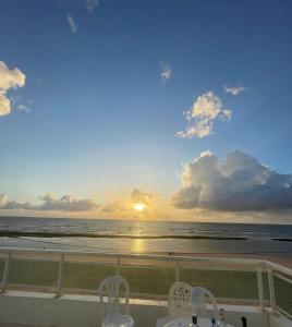 a view of the ocean at sunset from a balcony at CASA COM PISCINA À BEIRA MAR. in Recife