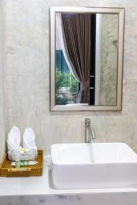 a bathroom with a white sink and a mirror at Rapina House in Mai Khao Beach