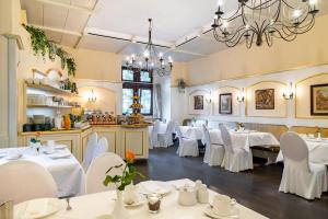 ein Restaurant mit weißen Tischen und Stühlen sowie einem Kronleuchter in der Unterkunft Burghotel Staufenberg in Staufenberg