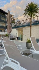 a patio with chairs and a umbrella and a palm tree at Padam Hotel & SPA in Ulcinj