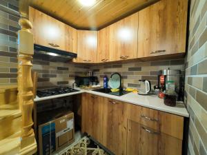 a kitchen with wooden cabinets and a stove top oven at Eldeniz Nuxa House in Sheki +5 photos