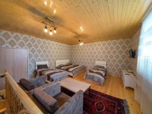 een kamer met vier bedden en een bank erin bij Eldeniz Nuxa House in Sheki