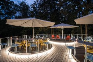 una terraza con mesas, sillas y sombrillas por la noche en Airbase Hotel, en Kalsdorf bei Graz