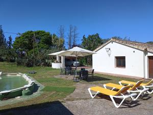a group of chairs and an umbrella next to a house at CAN VICENS in Caldes de Malavella