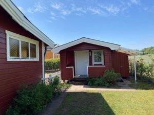 una casa roja con una puerta blanca en un patio en Ferienhaus in Tibro mit Kleinem Garten, en Tibro