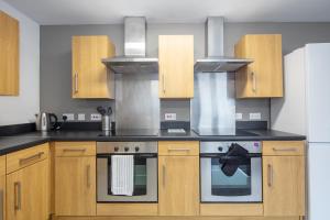 La cuisine est équipée de placards en bois et d'un four avec plaques de cuisson. dans l'établissement Charming Aberdeen Adult-Only Flats, à Aberdeen