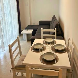 a dining table and chairs with a living room at Rana Hedhun Apartment in Margjonaj