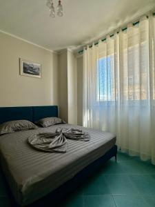 1 dormitorio con 1 cama grande y ventana en Eri Apartments, en Shëngjin