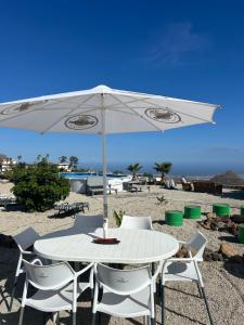 una mesa blanca y sillas con sombrilla en la playa en Casa Rural El Pasil en Arona