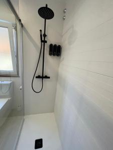 a shower in a white bathroom with a black shower head at Casa Mar y Sol in Corcubión