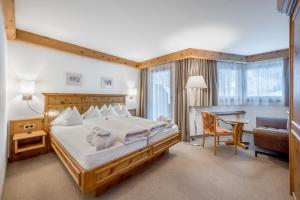 a bedroom with a large bed and a desk at Chalet Silvretta Hotel & Spa in Samnaun
