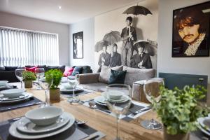 STARR SUITE 6 BEDS في ليفربول: غرفة معيشة مع طاولة مع أطباق وكؤوس للنبيذ