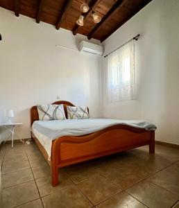 a bedroom with a wooden bed and a window at Tinos Beautiful Sunrise Apartment Near Agios Sostis Beach in Agios Sostis