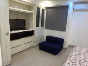 1 dormitorio con silla azul y TV en Escape Oceanfront Condo in Avenida Espana w/Pool en Santo Domingo