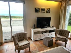 een woonkamer met een televisie en 2 stoelen bij Villa front de mer les Cordylines in Saint-Germain-sur-Ay