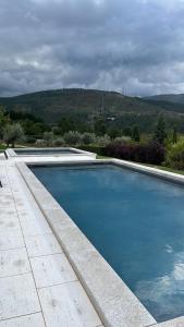 a large blue swimming pool with a mountain in the background at Casa do Lagar in Mondim da Beira