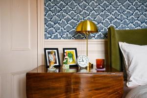 a nightstand with a clock and pictures on it next to a bed at The Dover Stop in Dover