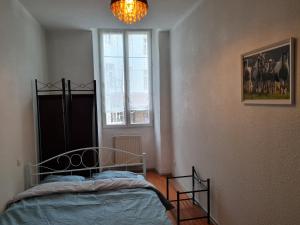 1 dormitorio con cama, ventana y lámpara de araña en Bel appartement spacieux en centre-ville, en Foix