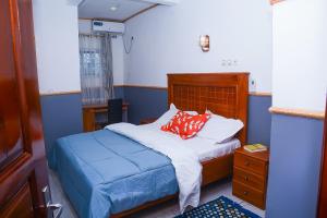 Habitación pequeña con cama y mesita de noche en Ajieh Rest House, en Douala