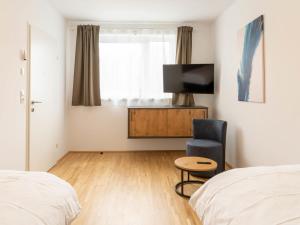 a bedroom with a bed and a tv and a chair at Apartment be blue by Interhome in Mieming