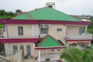une maison ancienne avec un toit vert dans l'établissement Ajieh Rest House, à Douala