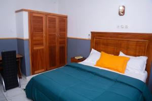 1 dormitorio con 1 cama con cabecero de madera en Ajieh Rest House, en Douala