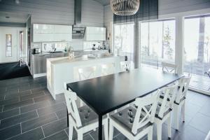 a kitchen with a black table and white chairs at SleepWell Villa Hartola in Kirkkola
