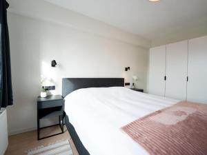 a bedroom with a large white bed and a black desk at Apartment 't zout by Interhome in Bredene +12 photos