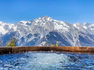 a swimming pool with snow covered mountains in the background at Chalet Chalet Gerritsen by Interhome in Nendaz