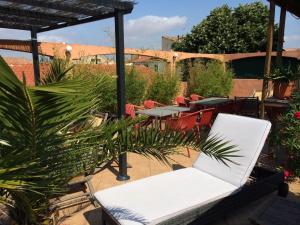 une terrasse avec un canapé blanc, des tables et des chaises dans l'établissement Hôtel Le Gambetta, à Vias