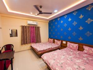 een kamer met 2 bedden, een bureau en een tafel bij Nirmal Luxury Rooms in Garudeshwar
