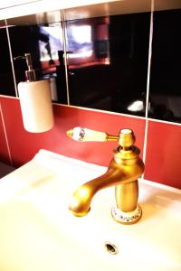 a bathroom sink with a gold faucet and a mirror at Gästehaus Ehringhausen 63 (Anno 1719) in Remscheid