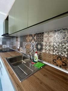 una cocina con fregadero de acero inoxidable y azulejos en Eri Apartments 2, en Shëngjin