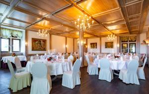 un salón de banquetes con mesas y sillas blancas en Burghotel Staufenberg en Staufenberg