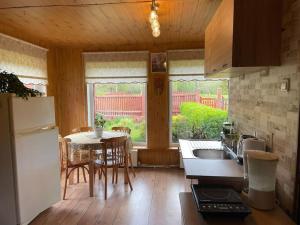 a kitchen with a table and a white refrigerator at Ligzdas in Valgalciems